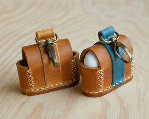 Ravenweave leather AirPods case flat lay, studio shot